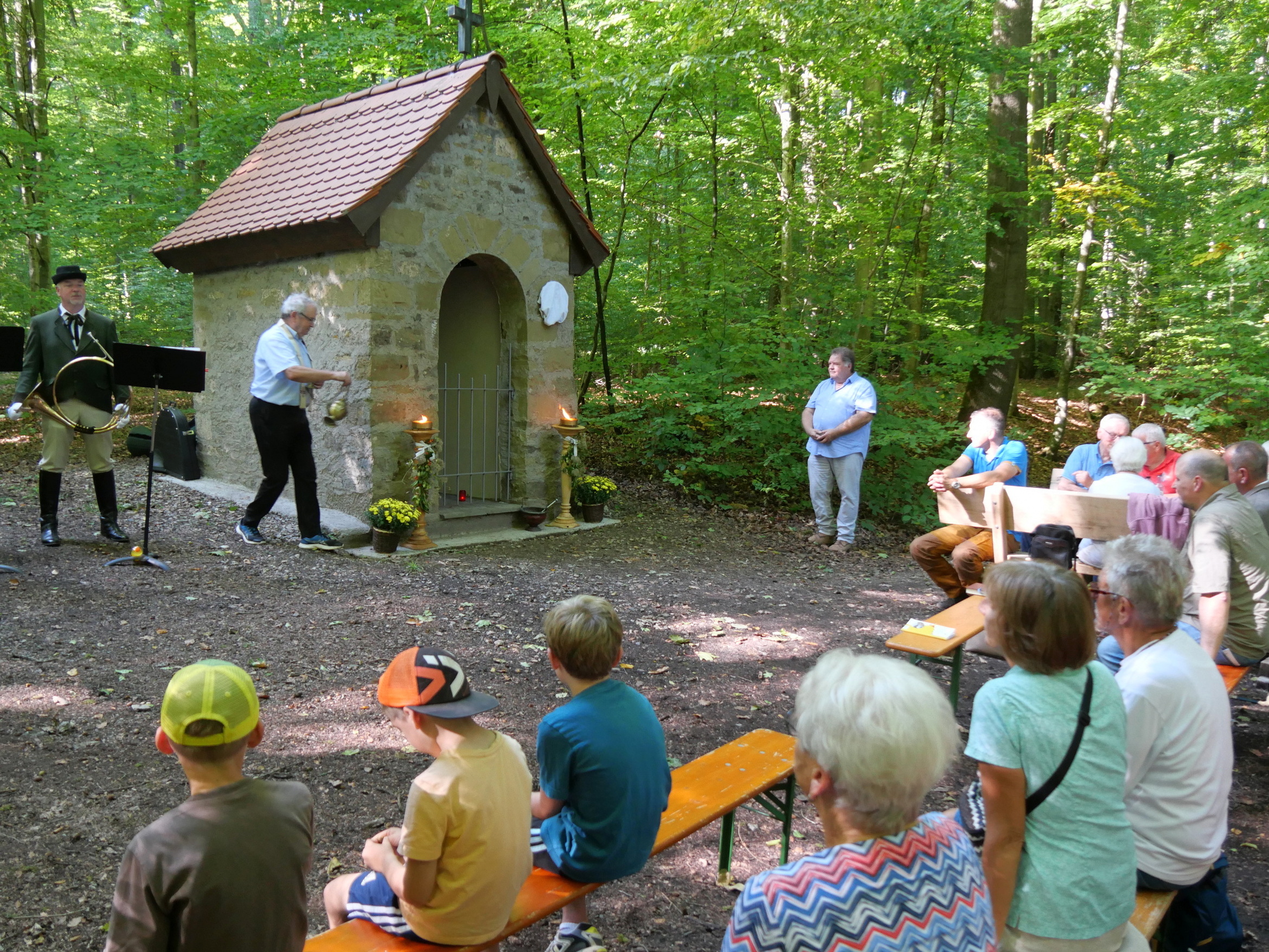 Der Pfarrer umrundet mit einem Weihrauchfass die kleine Kapelle.