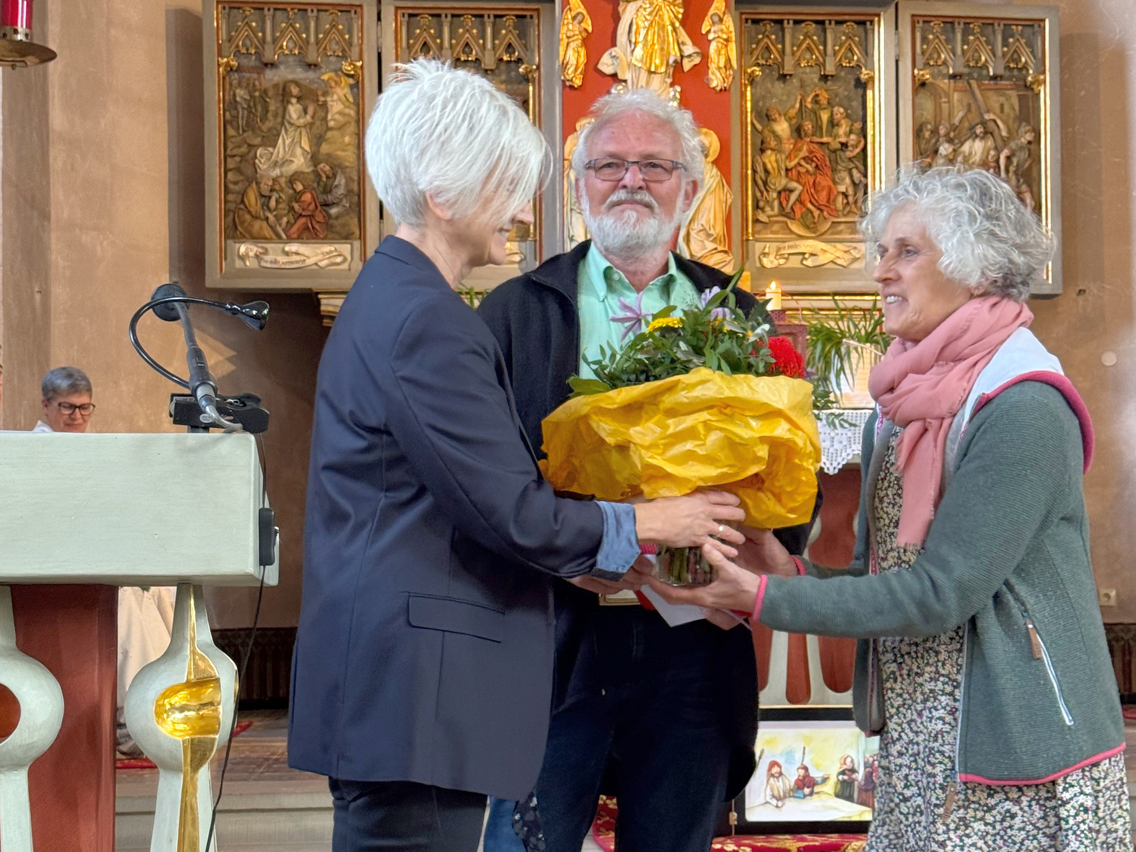 In der Kirche in Opferbaum bekommt Gertrud Endres einen Blumenstrauß. Links von ihr stehen Petra Eitzenbeger und ihr Mann Klaus Endres.
