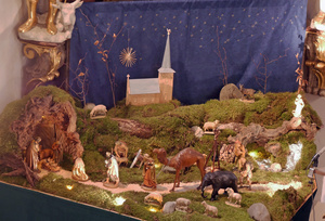 Die Krippe in der Kirche St. Wolfgang in Hausen mit der neuen Kirche aus Holz im Hintergrund.