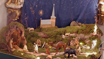Die Krippe in der Kirche St. Wolfgang in Hausen mit der neuen Kirche aus Holz im Hintergrund.