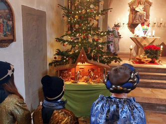 Blick vom Kirchenraum zum Altarraum. Links steht ein geschmückter Christbaum.