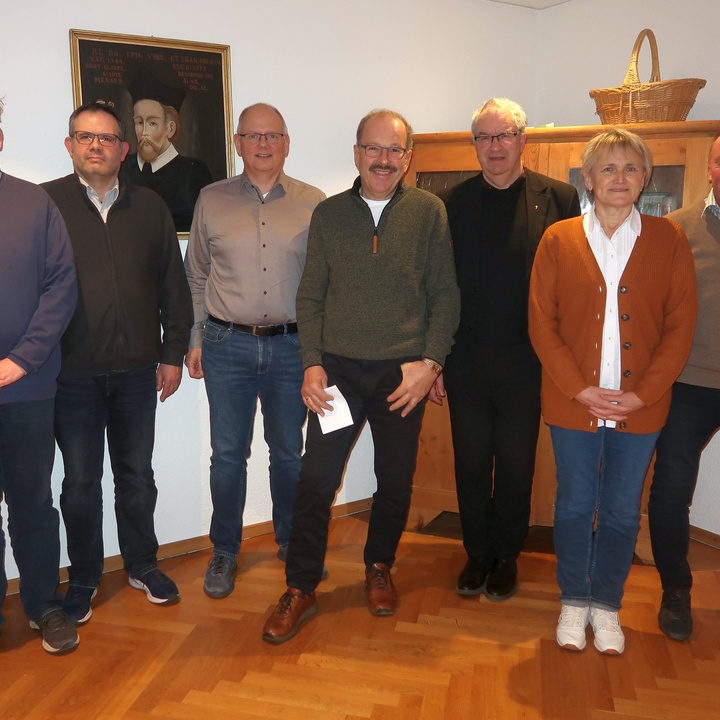 Das ist ein Gruppenbild mit sieben Personen. Der Pfarrer ist der dritte von rechts.