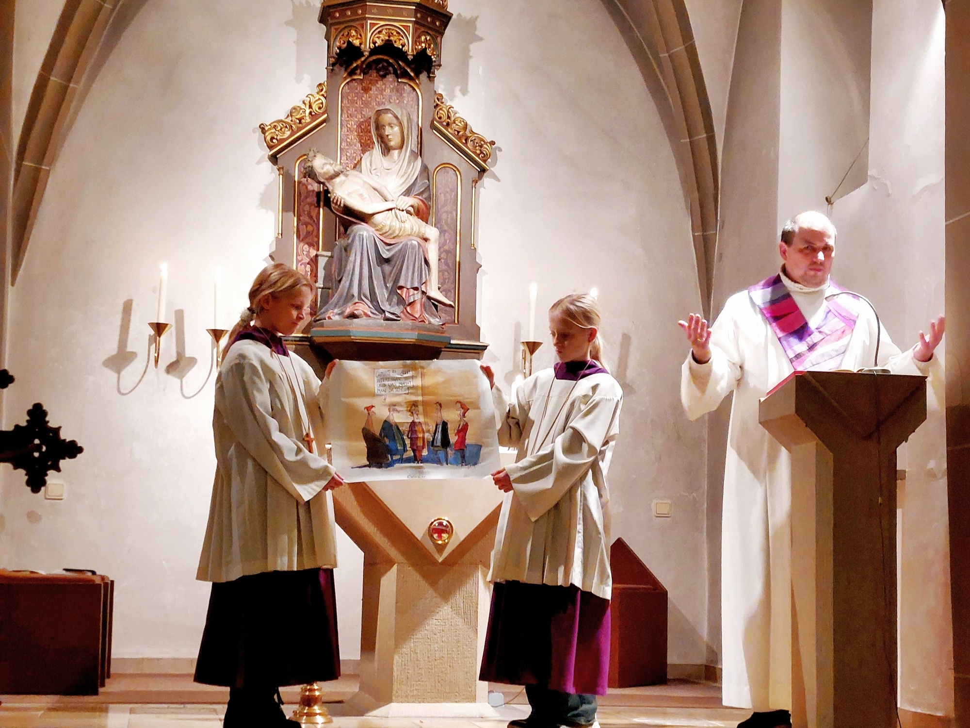 Florian Meier steht am Ambo und zwei Kinder zeigen ein Bild.