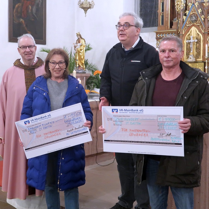 In der Burggrumbacher Kirche werden zwei große symbolische Schecks übergeben. 
