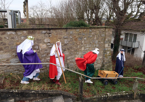 Das ist ein lustiges Bild. Vier Sternsinger gehen lachend einen Grashang hinunter.