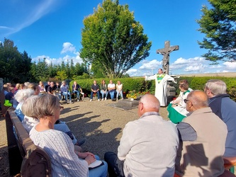 In einem Kreis sitzen Menschen um das Kreuz im Friedhof.