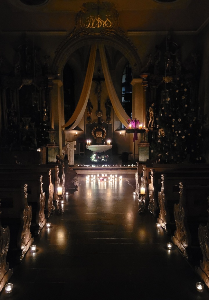 Blick von hinten den Mittelgang entlang zum Altar, die ganze Kirche wird nur durch Kerzenschein erleuchtet