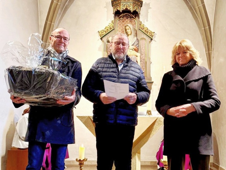 Auf dem Foto sind drei Personen mit Geschenken in den Händen. In der Mitte ist Norbert Brand.