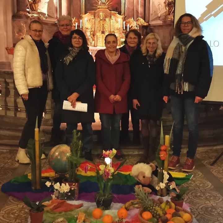 Sieben Frau stehen im Altarraum der Kirche. Vor ihnen einen Bodenbild, gestaltet mit bunten Tüchern, Früchten und Stofftieren.