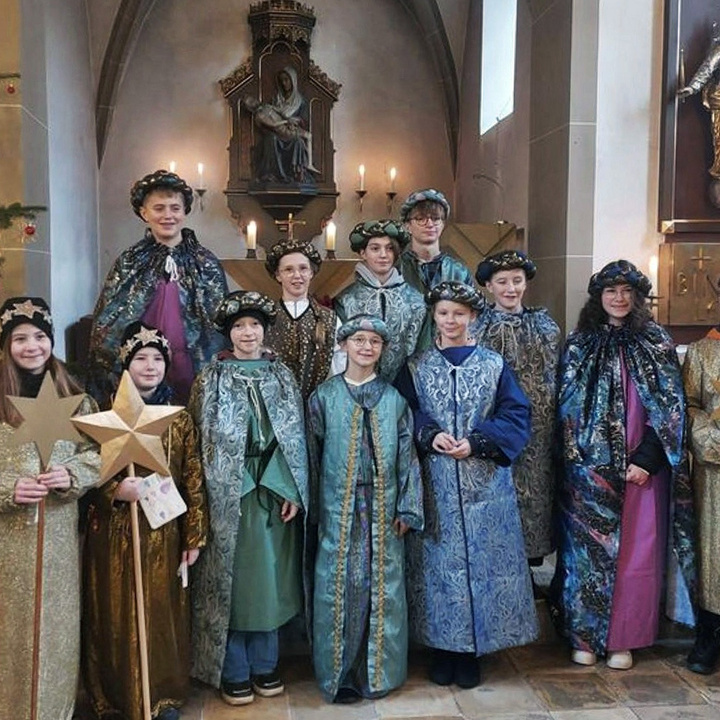Eine Gruppe von Kindern und Jugendlichen schaut in die Kamera. Sie sind als Sternsinger angezogen.