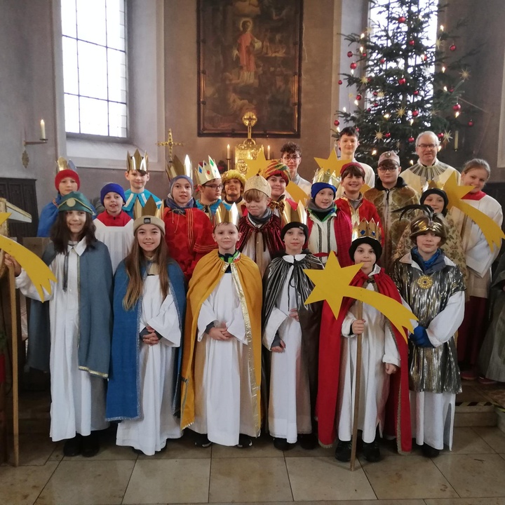 Die 22-köpfige Sternsingergruppe steht auf den Altarstufen in der Kirche. Alle schauen in die Kamera.