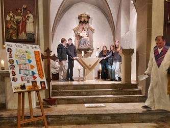Sechs Jugendliche stehen um den Altar in der Püssensheimer Kirche. Links ist ihr Firmplakat zu sehen.