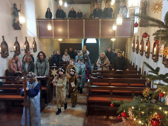 Blick vom Altarraum in die Kirche. Im Mittelgang ziehen die Sternsingerinnen und Sternsinger ein.